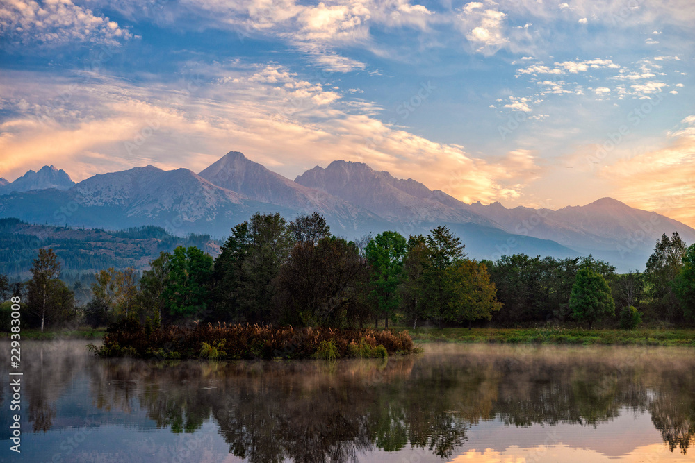 Obraz premium Peaceful autumn landscape with calm lake, colorful trees and low hanging fog/mist in a autumn time.