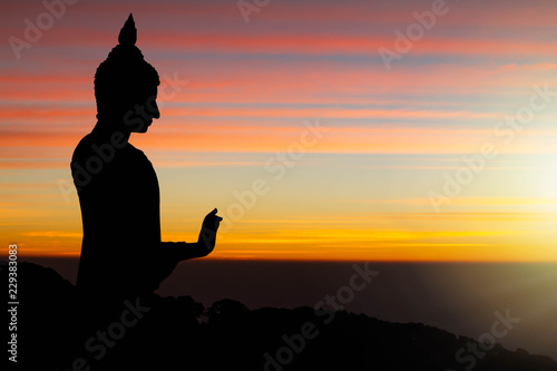 Silhouette of Buddha statue on sunrise background