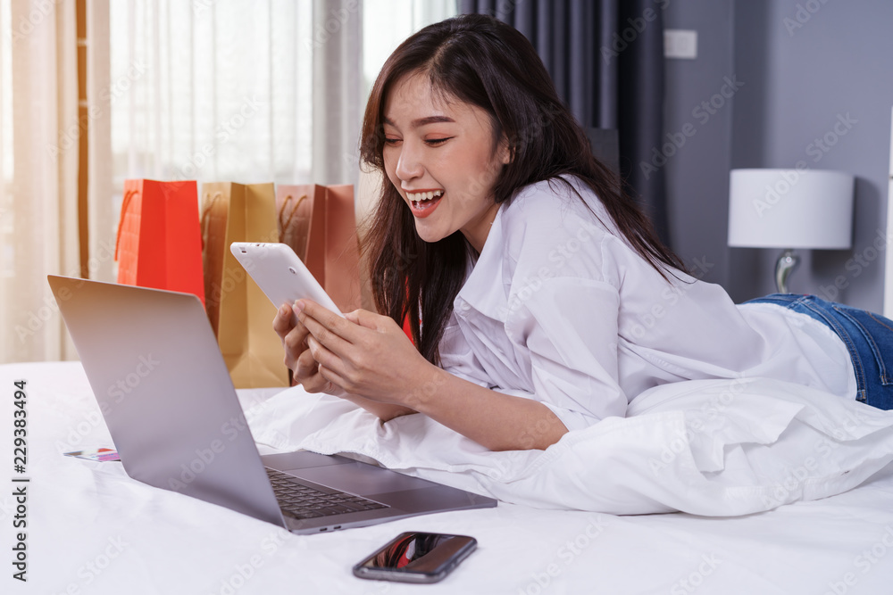 happy woman using tablet for online shopping on bed happy woman using tablet for online shopping on bed