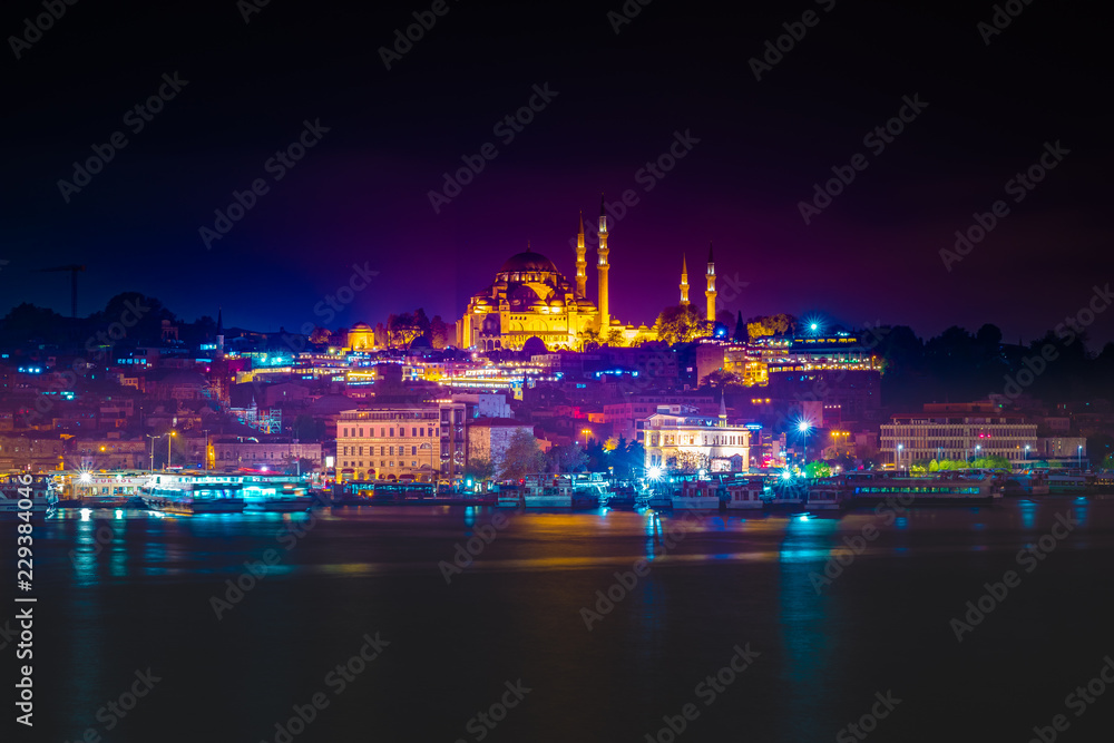 Night view to Suleymaniye Cami, from Galata Bridge, Istanbul, Turkey. Beautiful night view with colorful ships and reflection in the water of the Golden horn