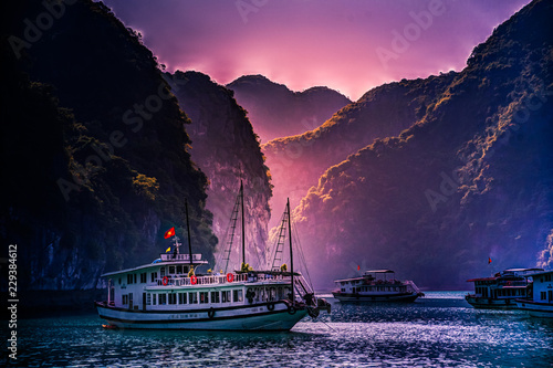 Stunning image of tourist cruise ship among green rocks in sunset light on Halong Bay, Vietnam photo