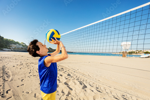 Teen boy passing ball playing beach volleyball