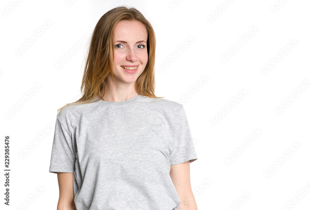 Portrait of a young woman in a gray t-shirt on a light background. Smiley face.