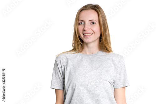 Portrait of a young woman in a gray t-shirt on a light background. Smiley face.