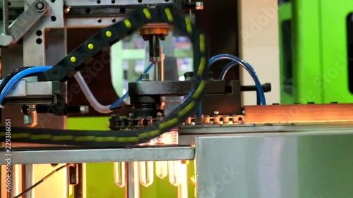 Close-up of industrial machinery to convey raw materials for the production of clear plastic bottles through a heating process, industry 4.0
