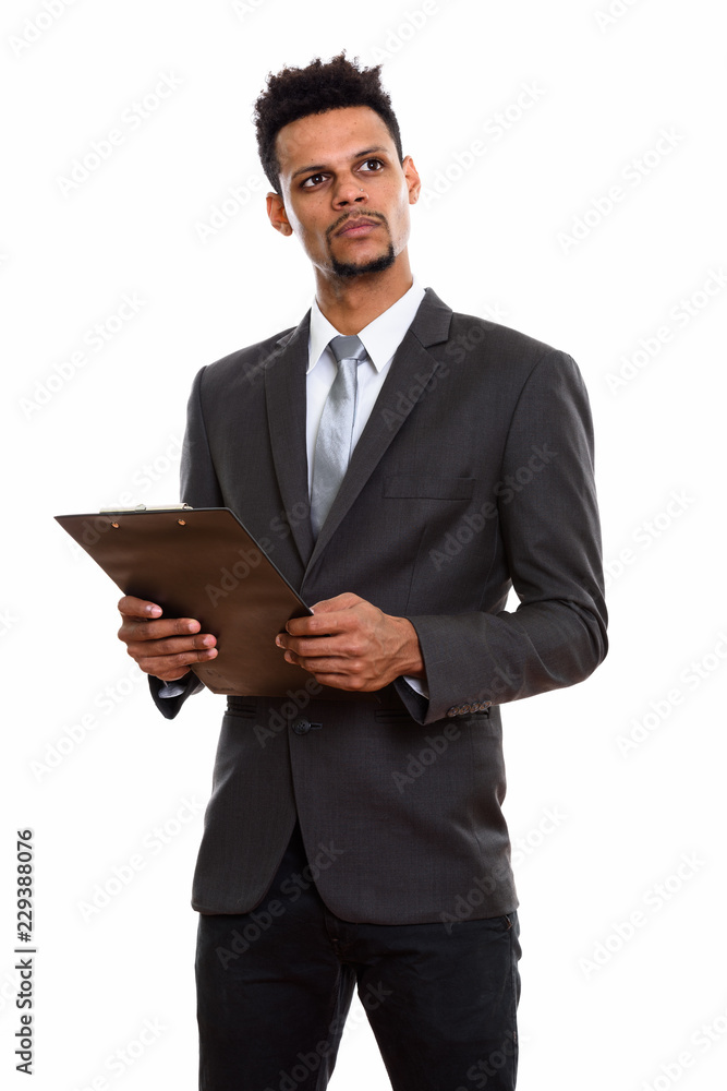 Young African businessman holding clipboard while thinking and l Young African businessman holding clipboard while thinking and l