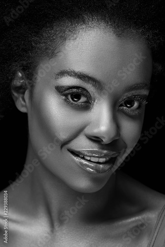 black and white photo of beautiful african american woman looking at camera isolated on black