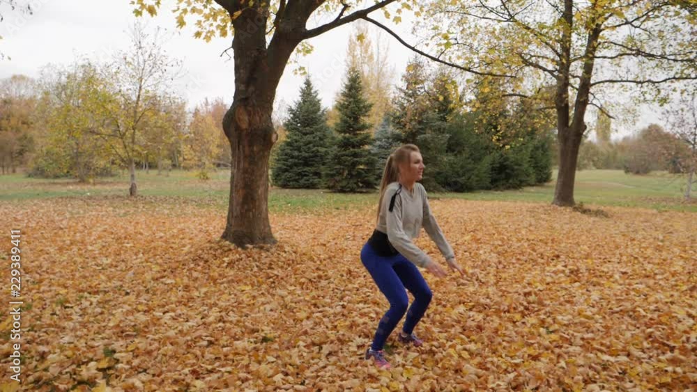 Young blonde female doing sports morning fitness workout in autumn park slow motion Young blonde female doing sports morning fitness workout in autumn park slow motion