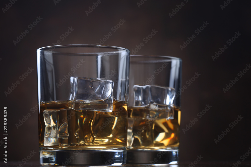 Glasses with whiskey and ice cubes