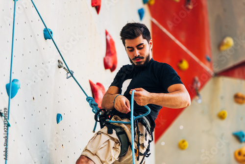 Young sporty man climbing up on practice mount wall outdoor