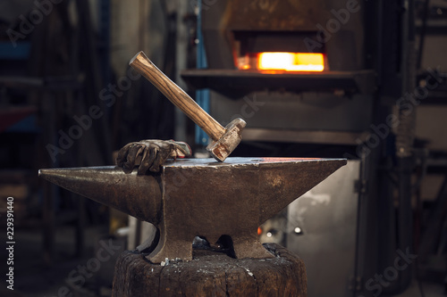 Quadro em tela Mallet and gloves on an anvil in front of a furnace