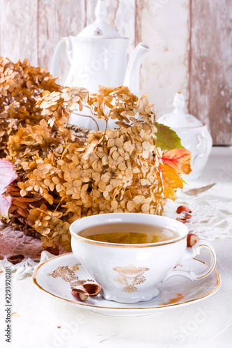 Tea in the rustic vintage Chic style. Garden tea Party. Teapot of dry flowers. Cup of tea with autumn decor on table, with hydrangea and pumpkin photo