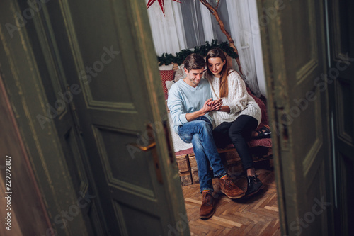 A guy with a girl is celebrating Christmas. A loving couple enjoy each other on New Year's Eve. New Year's love story. Man and woman enjoy the moment and playing with garlands. © nataliakabliuk
