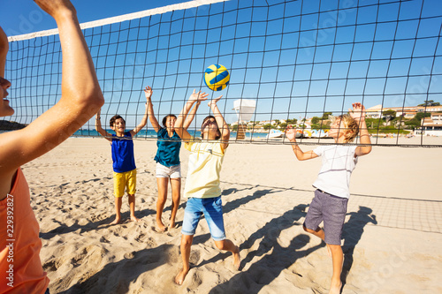 Happy friends playing beach volleyball in summer