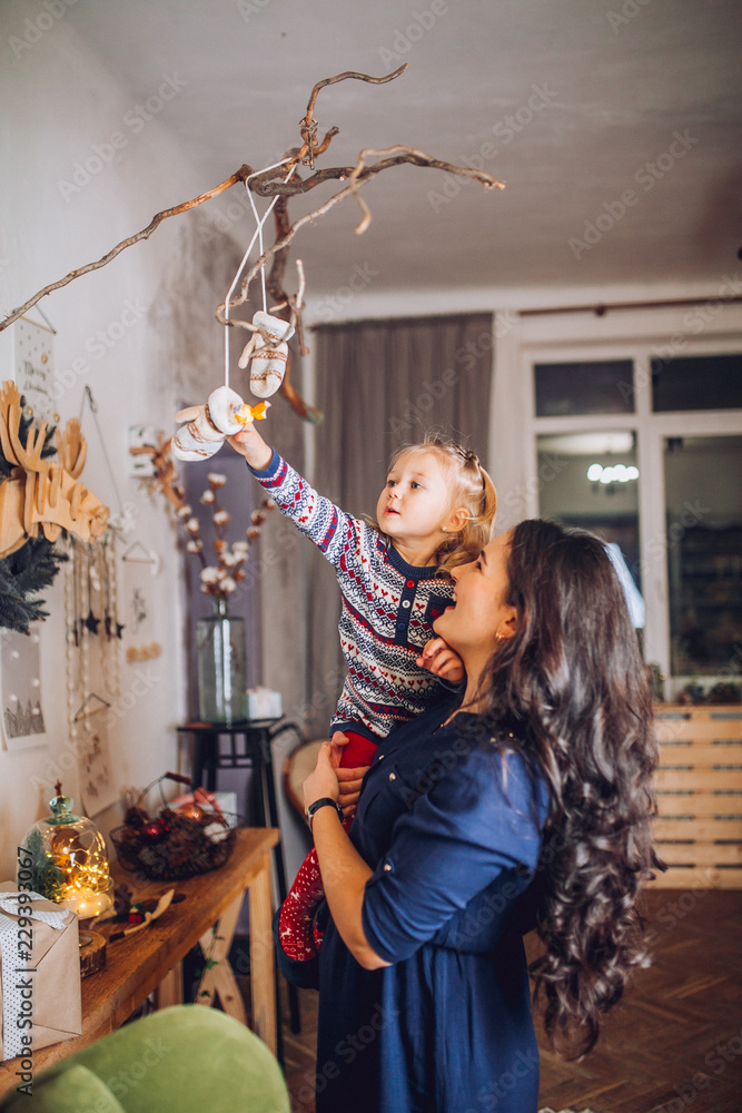 Portrait of beautiful mother and dauther near the Christmas tree. Family woman with little child in a festive New Year's atmosphere. Happy holiday moment. Portrait of beautiful mother and dauther near the Christmas tree. Family woman with little child in a festive New Year's atmosphere. Happy holiday moment.
