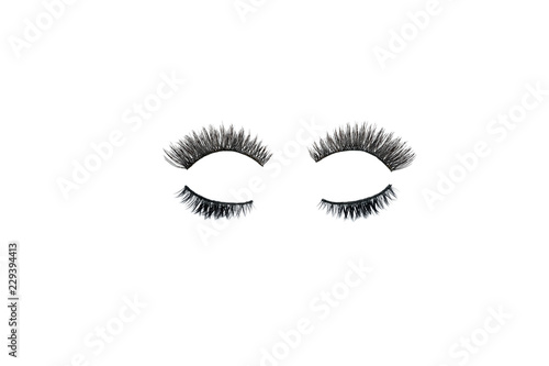 Dramatic black long false eyelashes placed in the shape of a human eye isolated on white background shot with studio light