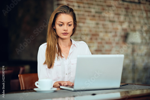 Businesswoman using laptop for work while sitting in cafeteria.