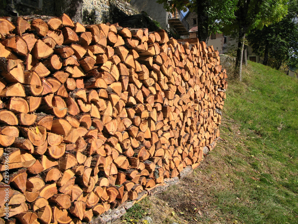 Pile de bois de chauffage devant une maison de village