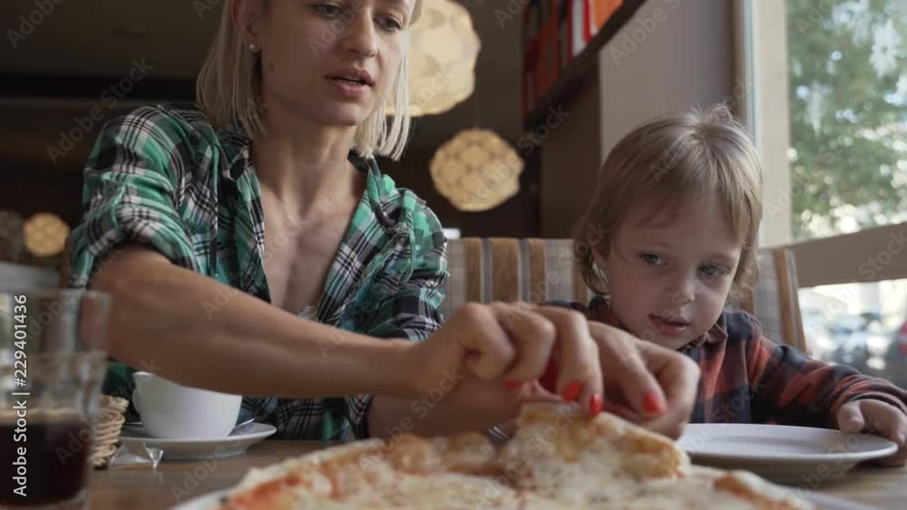 Woman and 5 year boy eating pizza in cafe