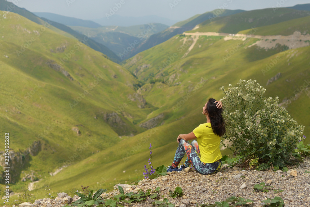 Young woman in sportswear against the green mountains in the Chechen Republic.