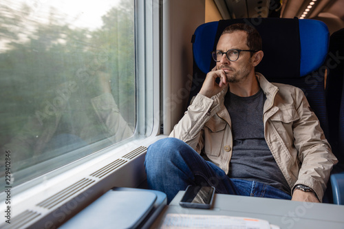 Middle age man looking out of the window of train. Passenger during travel by high speed express train in Europe