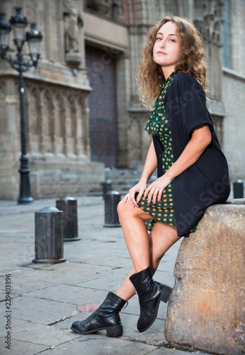Young girl tourist in dress sitting at stone bench in historical center
