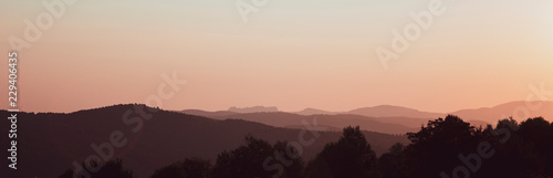 Dark tones of panoramic range mountains at sunset.