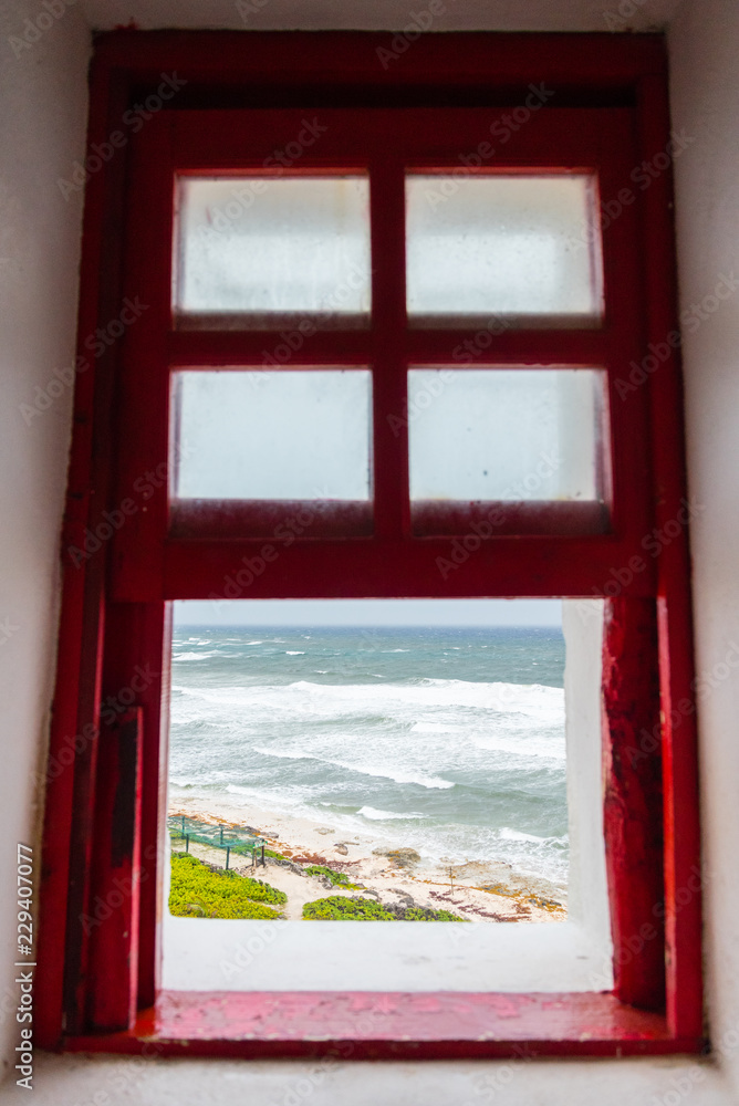 Fototapeta premium Ocean View through a Red-Framed Window in Mexico