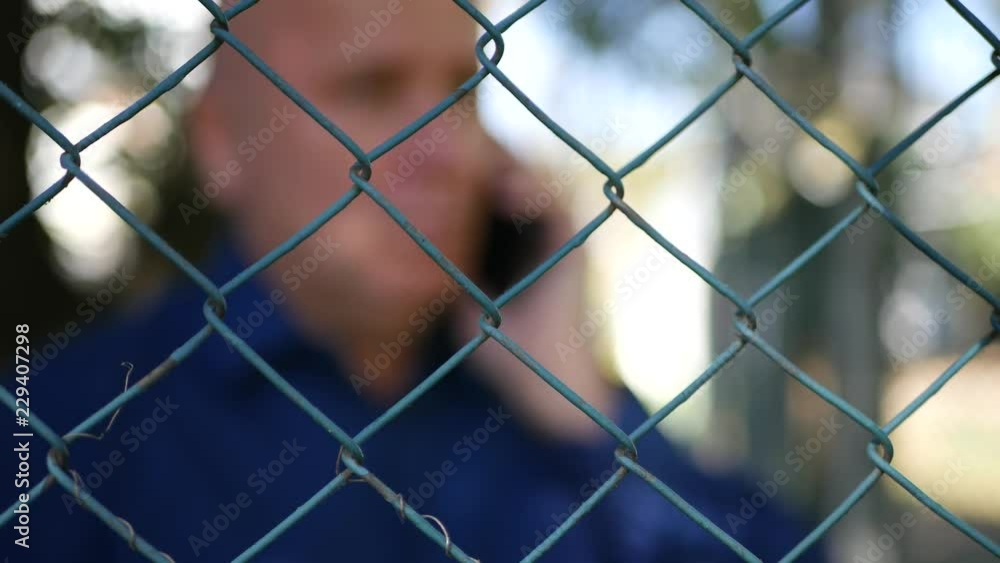 Blurred Shooting with Man Talking to Cellphone Behind of a Metallic Fence Blurred Shooting with Man Talking to Cellphone Behind of a Metallic Fence