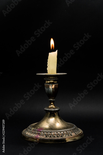 Vintage candlestick with burning candle in black background
