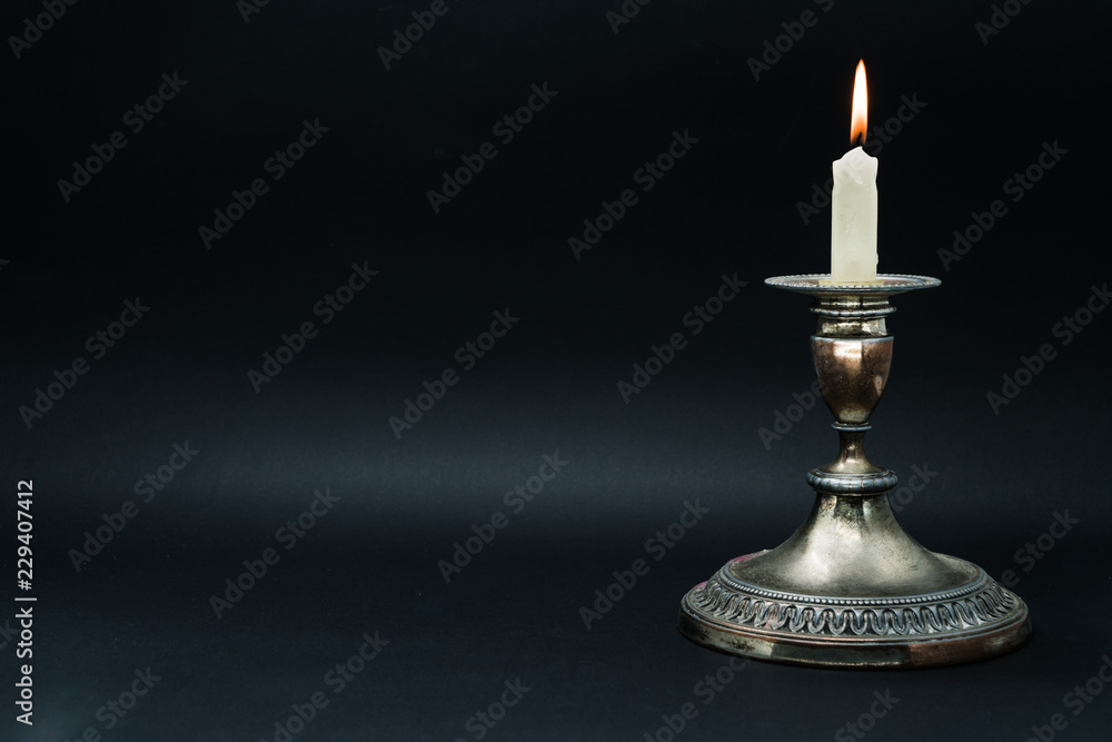 Old silver candle holder with lighted candle