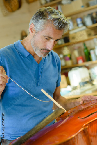 Obraz na plátně Closeup of craftsman making musical instrument bridge