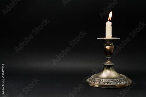 Vintage candle holder with lighted candle isolated in black background