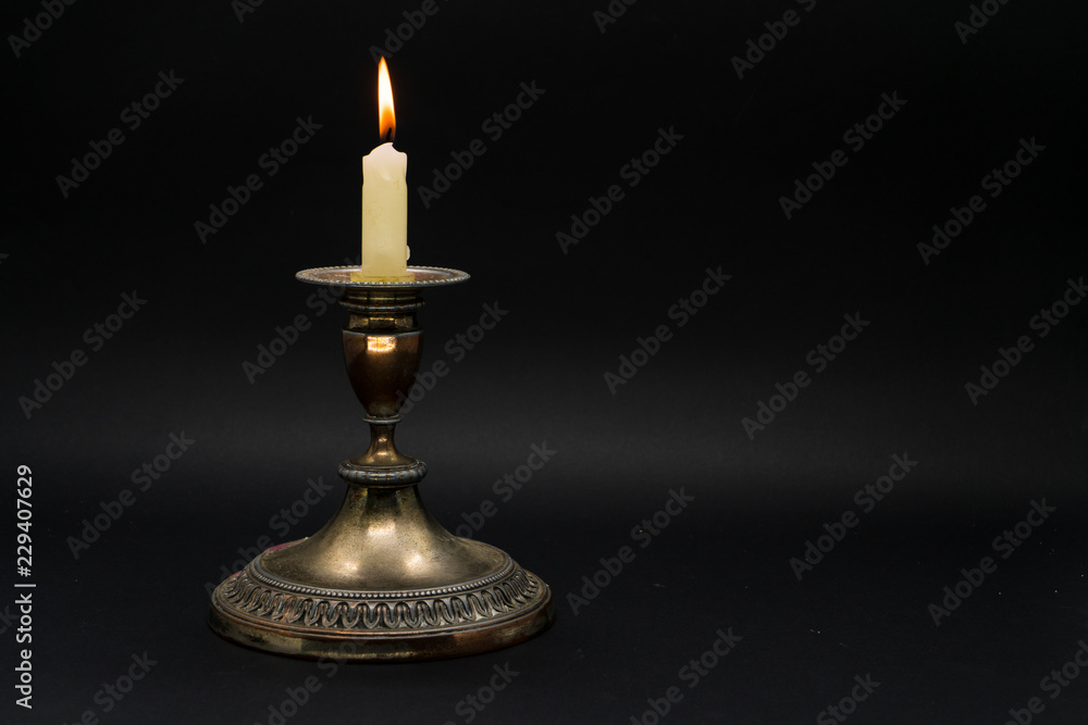 Vintage candle holder with lighted candle isolated in black background