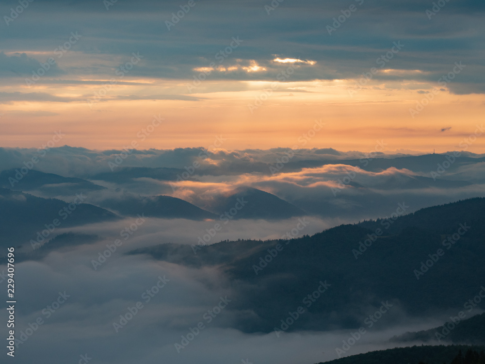 Landscape of mountains, clouds and sun going west. Carpathians mountains in august, west Ukraine. Nature background. Sun illuminating white clouds in the evening. Blurred background