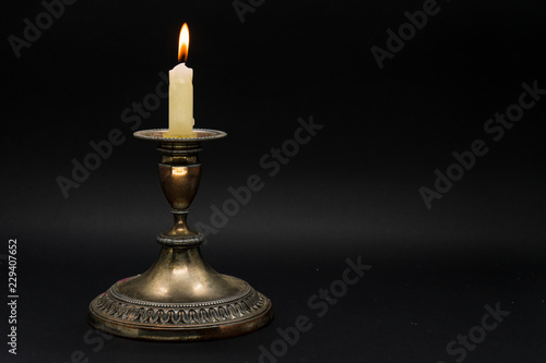 Vintage candle holder with lighted candle isolated in black background