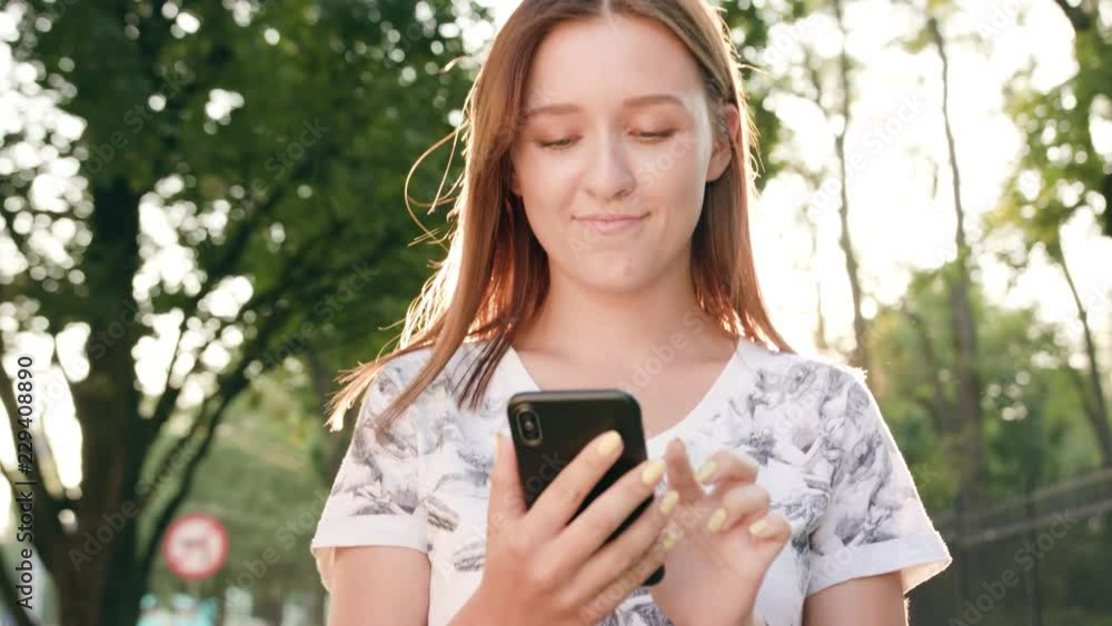 An attractive young lady using a phone in town while walking. Close-up dolly shot. Soft focus An attractive young lady using a phone in town while walking. Close-up dolly shot. Soft focus