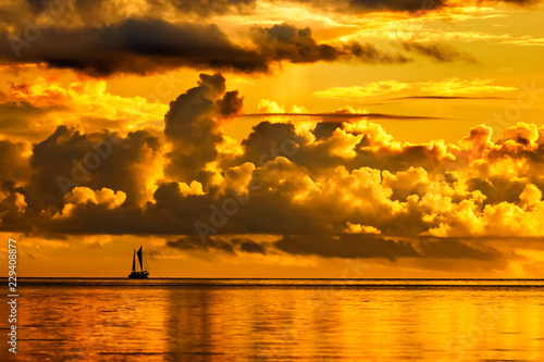 Silhouette of a sailing boat at dramatic golden sunset