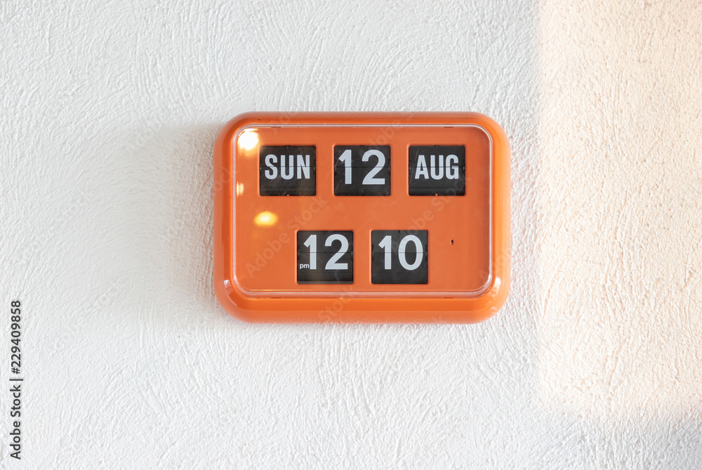 orange flip clock on white wall, retro analog timer. show time on 12 august at lunch time. orange flip clock on white wall, retro analog timer. show time on 12 august at lunch time.