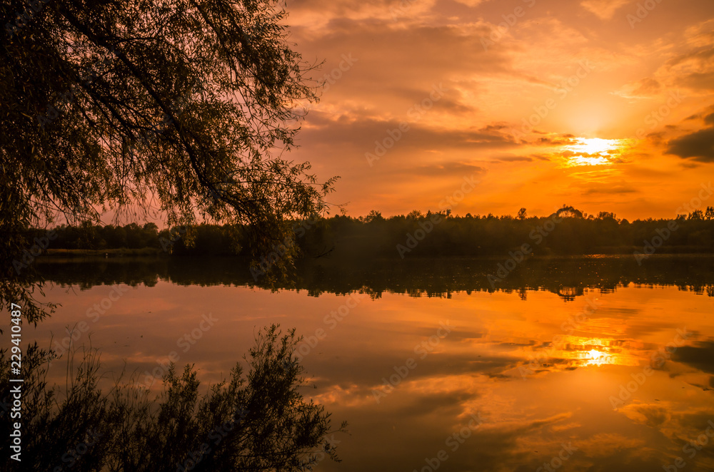 Sunset over a river delta in fall. Autumn evening landscape with a lake surrounded by reeds and straw Sunset over a river delta in fall. Autumn evening landscape with a lake surrounded by reeds and straw