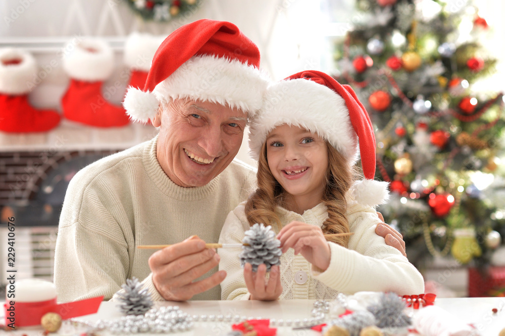 Portrait of happy grandfather and child in Santa hats preparing for Christmas Portrait of happy grandfather and child in Santa hats preparing for Christmas