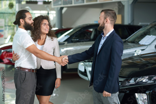 Fototapeta Naklejka Na Ścianę i Meble -  Couple shaking hands with car dealer, buying automobile. 