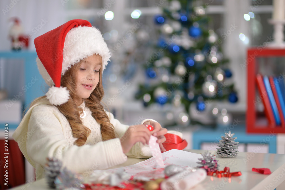 Portrait of cute little girl in Santa hat preparing for Christmas Portrait of cute little girl in Santa hat preparing for Christmas