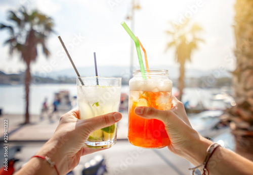 Cocktails with straws in a glass in human hands on background of the city, leisure and travel, entertainment, bars and restaurants, refreshments