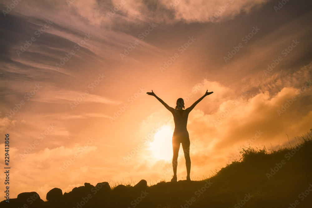 Silhouette of woman with her arms raised