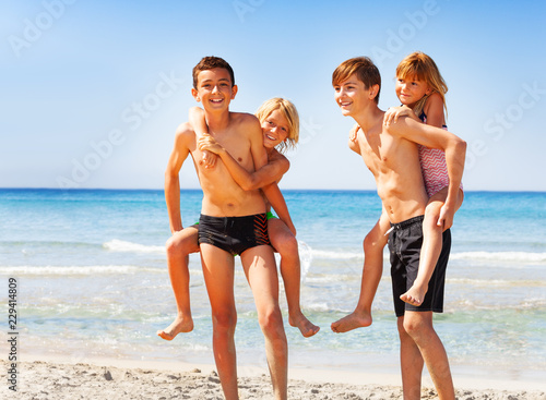 Happy boys piggybacking their friends on the beach