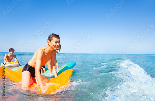 Happy boys riding the waves on air mattresses