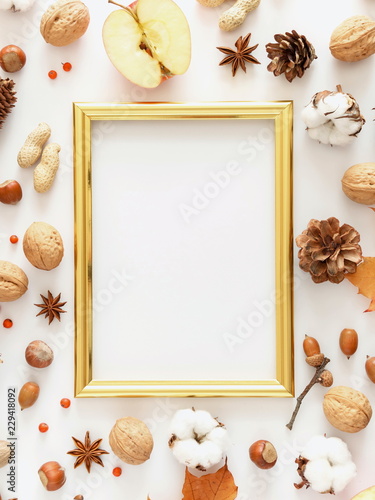Autumn, fall concept. Blank mock up photo frame, orange leaves, cotton flowers, pine cone, anise star, berries, nuts on white background. Flat lay, top view, copy space 