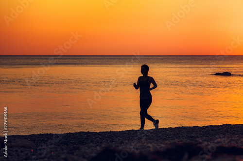 Silhouette of running women. Sea at sunset on the background