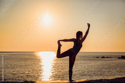 Silhouette of asana at the sunset. Sea on the background